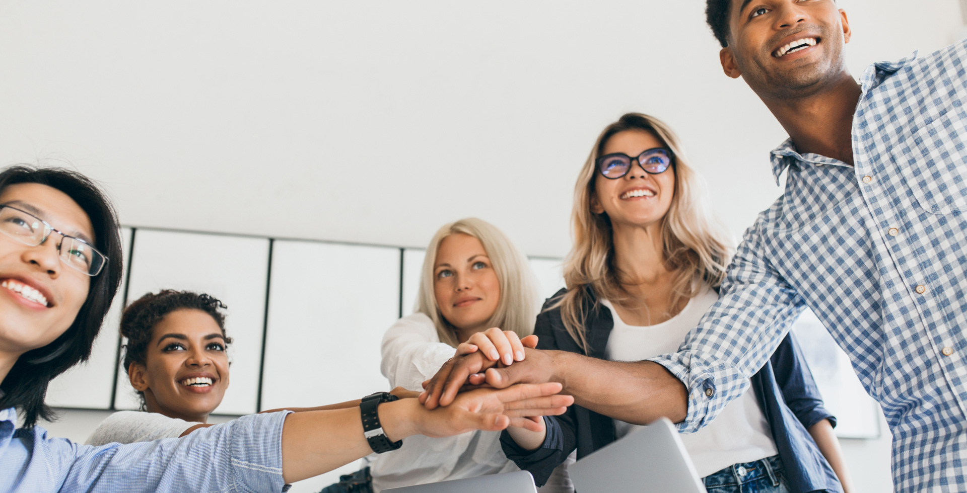 Image of a group of young people hands all joined and smiling